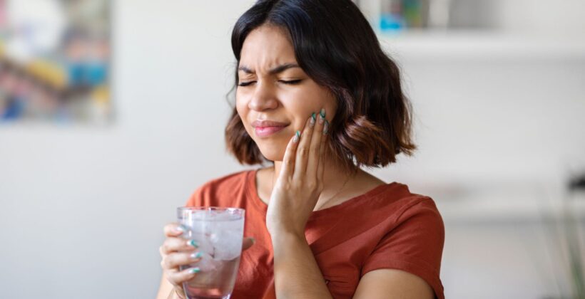 Woman experiencing tooth sensitivity to cold - getting insights into the questions of why are my teeth sensitive, with Midland Bay Dental.