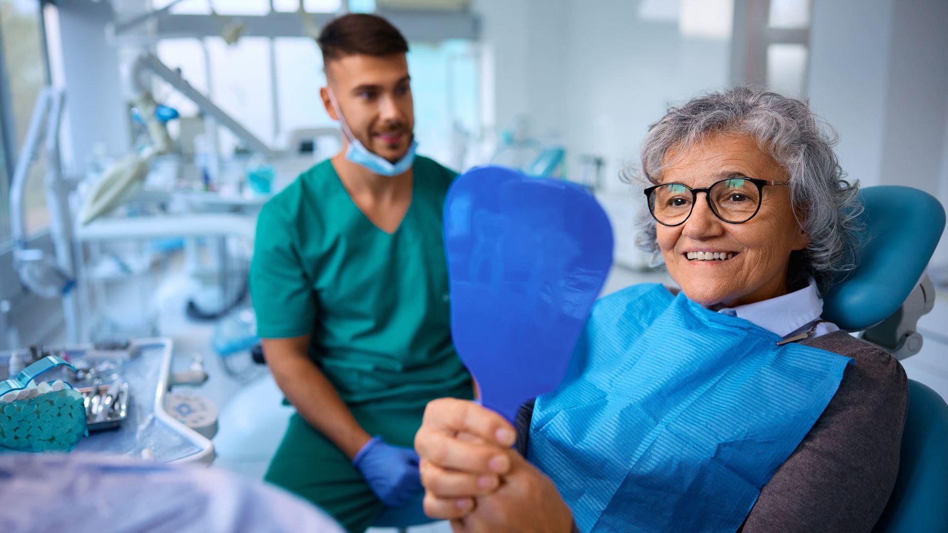 Woman looking in a mirror - crown and bridge support with Midland Bay Dental.