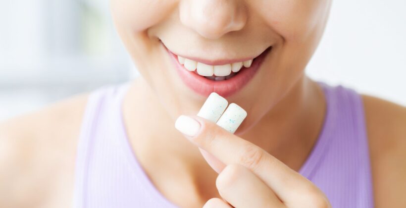 Faceless woman putting two pieces of gum into her mouth - is chewing gum good for your teeth - tips from Midland Bay Dental.