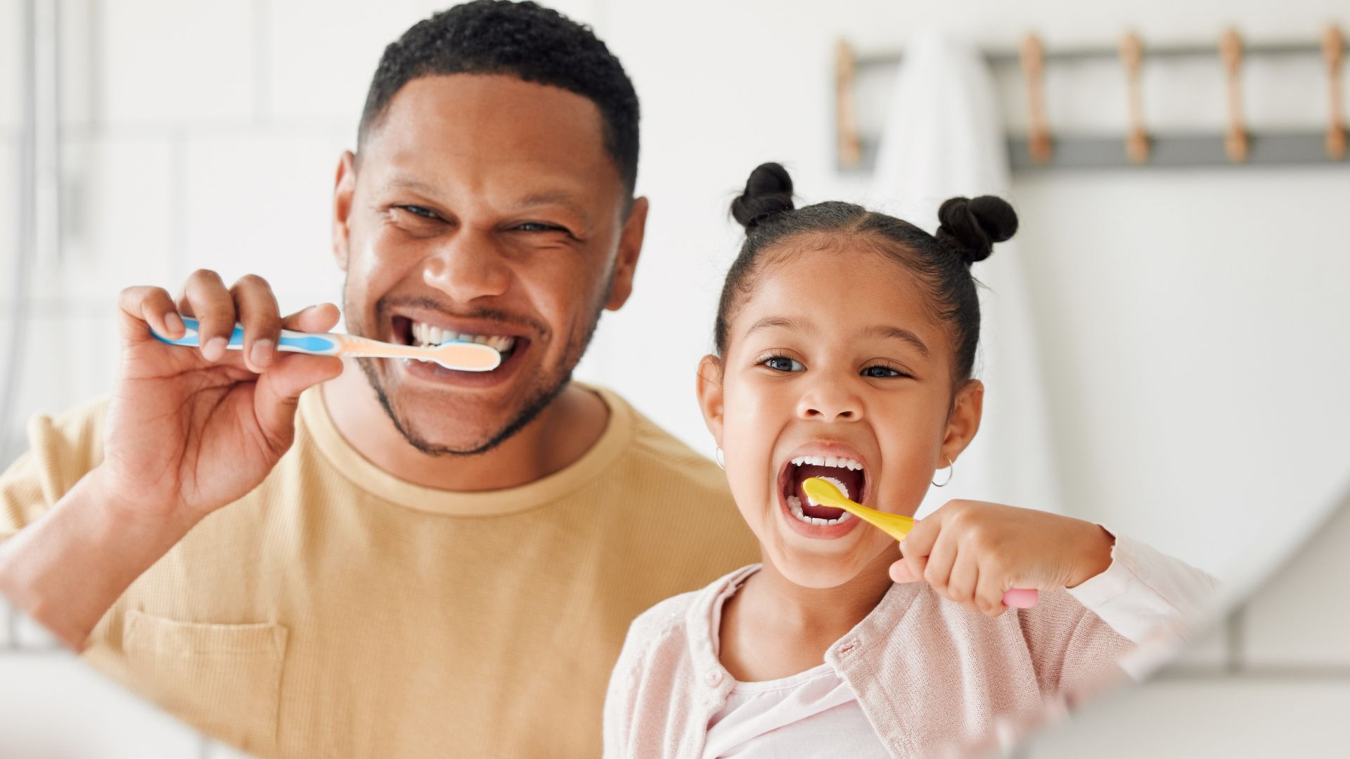 Dad and daughter brushing teeth together - how often should you change your toothbrush - Midland Bay Dental.